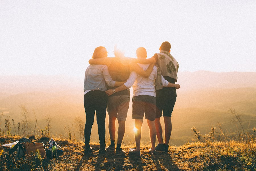 Four friends standing together in the warm light of sunset